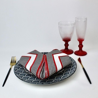 Conjunto de mesa com prato decorado, guardanapo dobrado, talheres e copos de vidro vermelhos texturizados