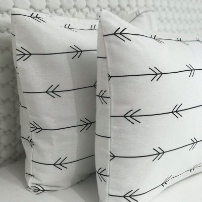 Almofadas brancas com padrão de setas pretas, tecido texturado, parede acolchoada branca