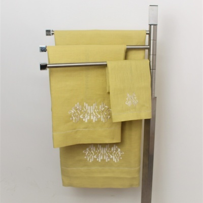 Toalhas amarelas bordadas penduradas em suporte metálico prateado