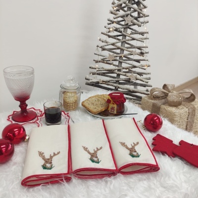 Três guardanapos com rena, copos, bolachas, pão, compota e decoração de Natal