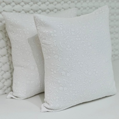 Duas almofadas quadradas brancas com padrão floral em relevo