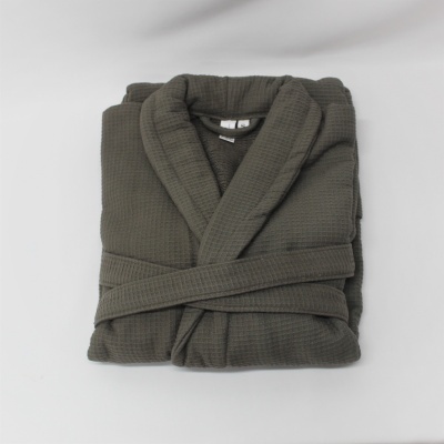 Roupão cinzento-escuro dobrado com cinto sobre superfície branca