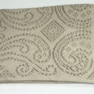 Manta bege com padrão geométrico e franjas numa extremidade