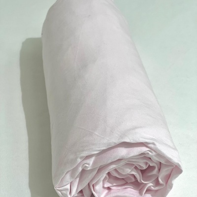 Lençol cor de rosa claro enrolado sobre superfície branca