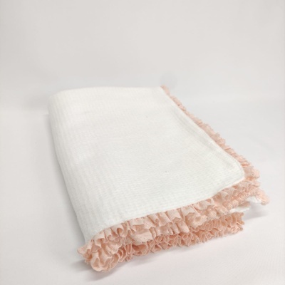 Toalha branca com barra de folhos rosa claro sobre superfície branca