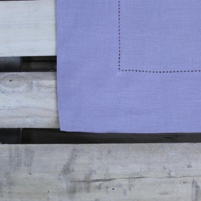 Toalha lilás com borda decorativa sobre madeira clara