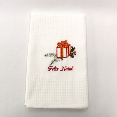 Toalha branca com bordado de presente de Natal e texto Feliz Natal