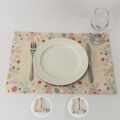 Mesa posta com prato branco, talheres em metal, copo de vidro e individual floral colorido