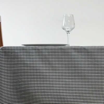 Toalha de mesa xadrez branco e preto com prato e taça de vidro sobre mesa de madeira