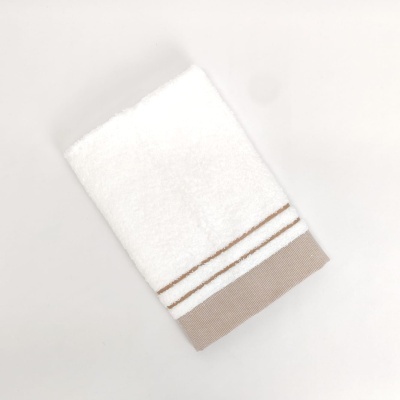 Toalha branca com borda bege e riscas brancas