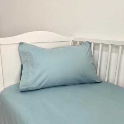 Cama de bebé branca com roupa de cama azul claro