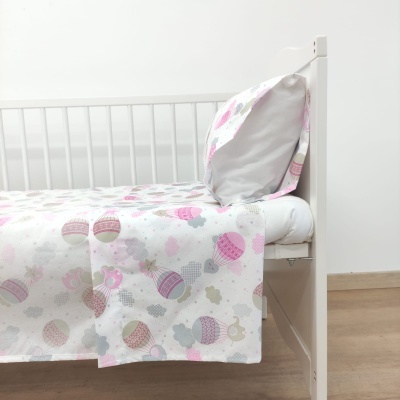 Cama branca de criança com roupa de cama colorida com balões de ar quente