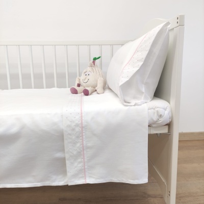 Cama branca com roupa de cama branca com linha rosa e peluche de ameixa.