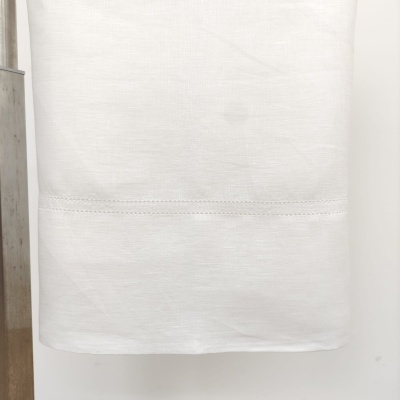 Pano de tecido branco com costura pendurado em suporte metálico