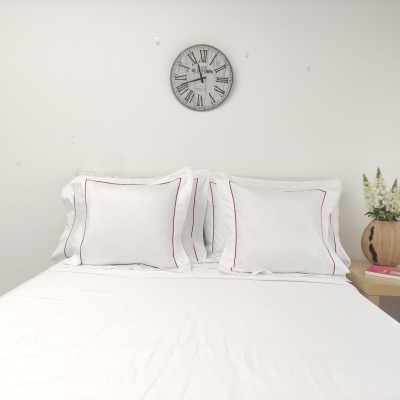 cama com almofadas brancas e relógio de parede sobre fundo branco