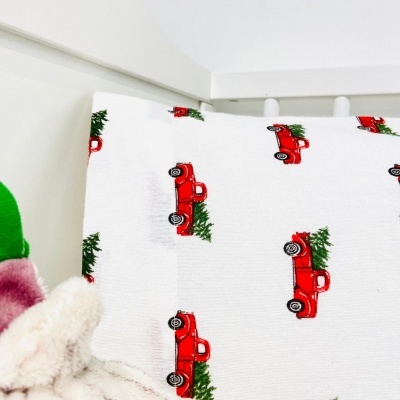 Fronha branca com carrinhos vermelhos e árvores de Natal verdes em berço branco