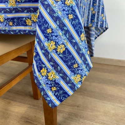 Toalha de mesa azul com flores amarelas e riscas, sobre mesa de madeira.