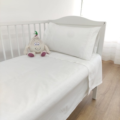 Cama de criança branca com roupa de cama branca e peluche de cordeiro