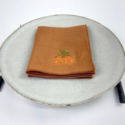 Guardanapo castanho bordado sobre prato cinza claro numa mesa com toalha branca