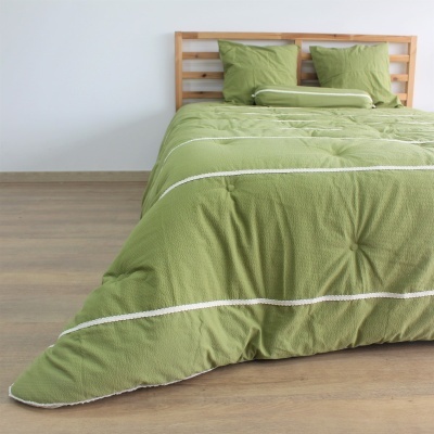 Roupa de cama verde com almofadas e cabeceira de madeira