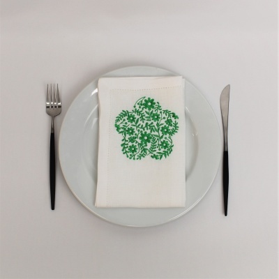 Conjunto de jantar com talheres pretos, prato branco e guardanapo branco bordado em verde