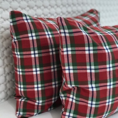 Almofadas xadrez em tartã vermelho, verde, branco e azul sobre superfície branca texturizada
