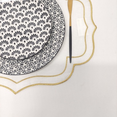 Pratos decorativos preto e branco com garfo e toalha branca bordada em dourado