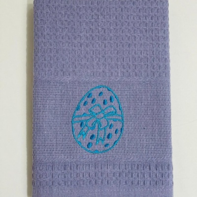 Toalha de cozinha lilás com bordado azul em forma de ovo decorado