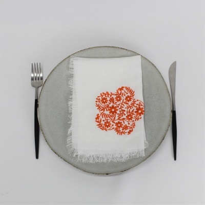 Prato cinza claro com guardanapo branco bordado e talheres ao lado