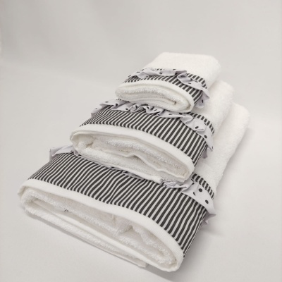 Conjunto de três toalhas brancas com bordas decorativas às riscas e laços pretos e brancos