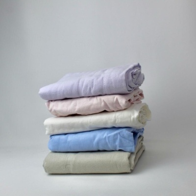 Pilhas de toalhas ou tecidos dobrados em cores lavanda, rosa claro, branco, azul claro e cinza claro