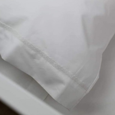 Travesseiro com fronha branca sobre lençol branco