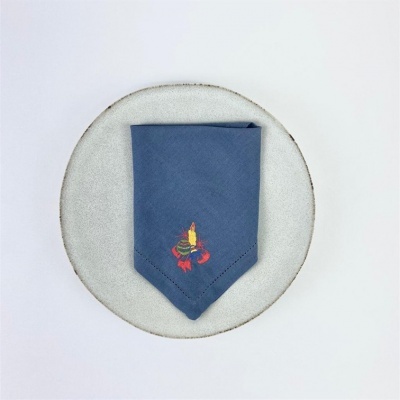 Guardanapo azul com bordado de velas no prato cinza