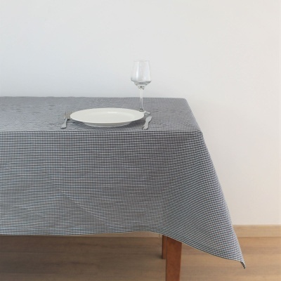 Mesa com toalha xadrez preta e branca com prato, talheres e copo