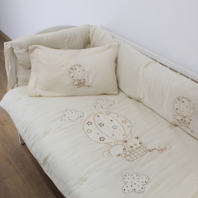 Colchão para berço bege com estampas bordadas e almofada correspondente