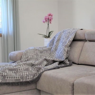 Cobertor cinzento com padrão num sofá bege