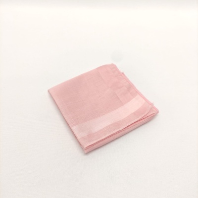 Lenço de tecido rosa claro dobrado com faixa clara nas bordas