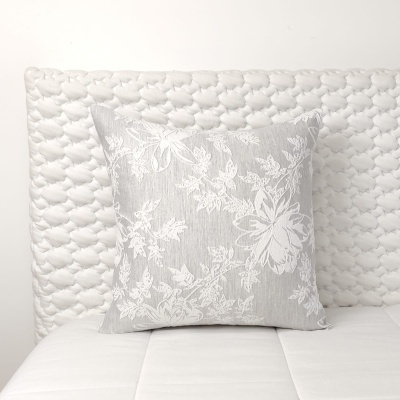 Almofada cinza floral sobre cama branca acolchoada