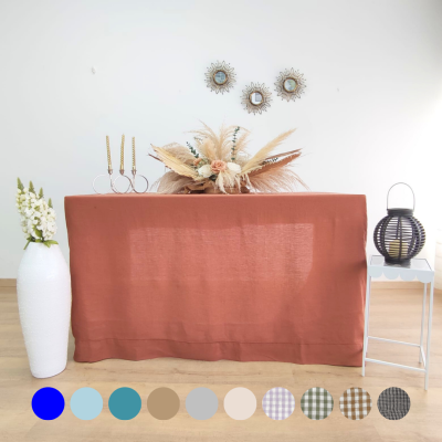 Mesa com toalha terracota e decoração floral seca com castiçais e espelhos na parede, vaso branco e lanterna preta ao lado.