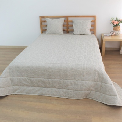 Cama de casal com edredão cinza claro e almofadões, estrutura de madeira, mesa de cabeceira com flores