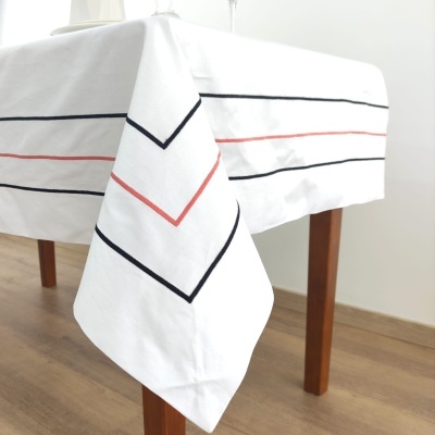 Toalha de mesa branca com riscas horizontais finas em preto e vermelho sobre mesa de madeira