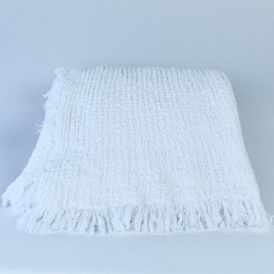 Manta branca com franjas e padrão quadrado