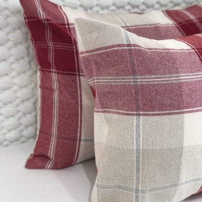Almofadas xadrez vermelha, bege e cinza em tecido macio com fundo texturizado branco