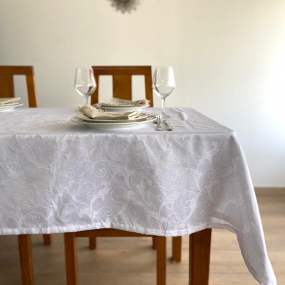 Toalha de mesa branca com padrão floral em mesa de madeira com utensílios de jantar