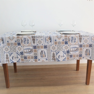 Toalha de mesa estampada com padrões azuis e bege em mesa de madeira com copos e pratos.