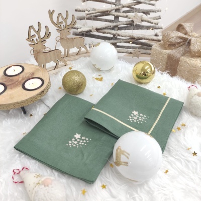 Guardanapos verdes natalícios com bordados dourados rodeados por decorações de Natal
