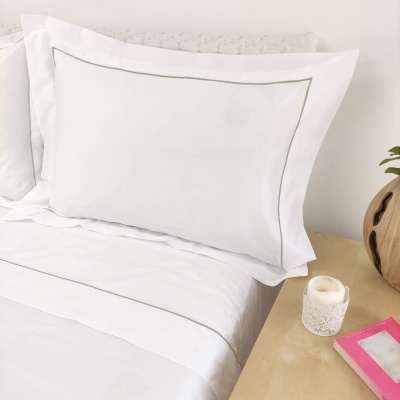 Roupagem de cama branca com risca cinzenta e mesa de cabeceira com vela e livro