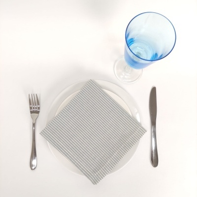 Conjunto talheres com prato, guardanapo e copo azul sobre superfície branca