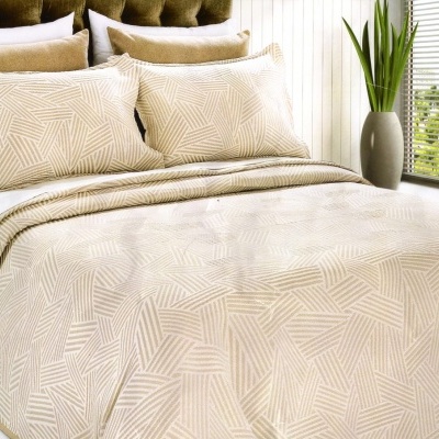 Conjunto de cama bege com padrão geométrico e edredão num quarto moderno com janela e planta