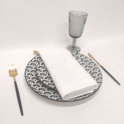 Conjunto de prato, guardanapo, talheres e copo em mesa branca